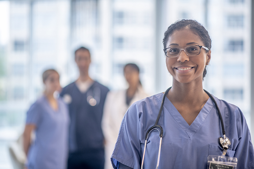 A smiling nurse stands in front of a group of other nurses.